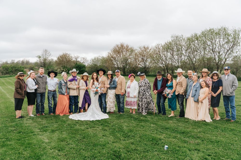 Wedding party poses in a row on grassy hillside during outdoor spring celebration.