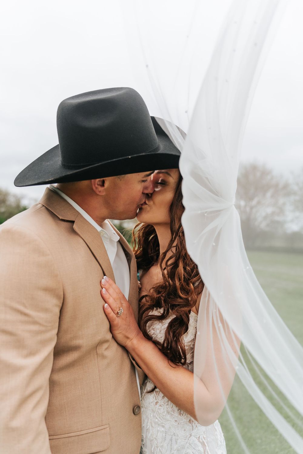 A romantic moment captured through flowing white curtains in an outdoor setting with soft natural lighting.