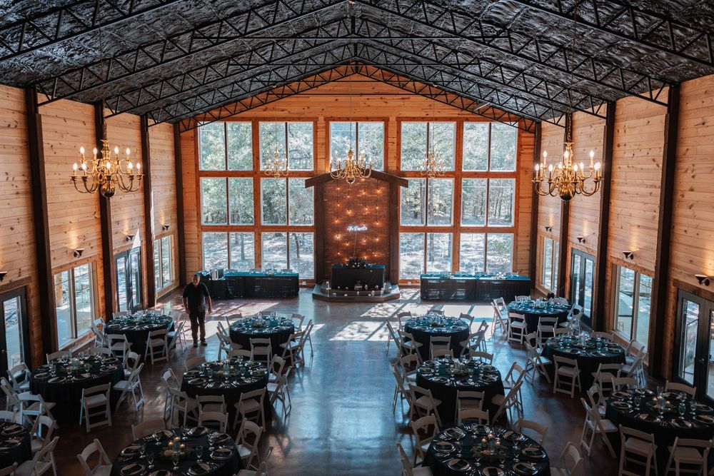 A spacious industrial-style event venue with exposed brick walls, chandeliers, and large windows letting in natural light.