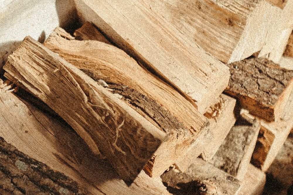 Stack of freshly chopped and split firewood logs arranged in rows for winter heating.