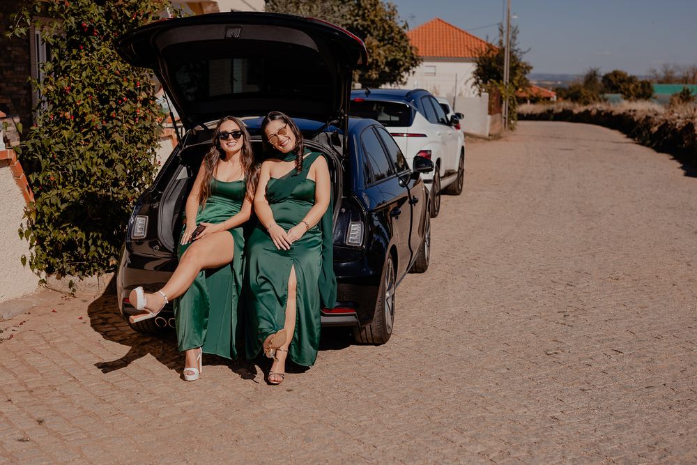 Bridesmaids in emerald green dresses pose on a sandy beach.