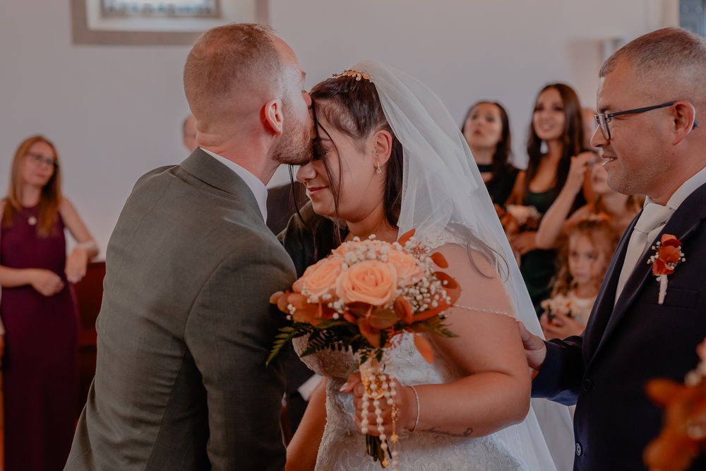 Intimate wedding ceremony moment with couple exchanging vows in front of guests wearing burgundy dresses.