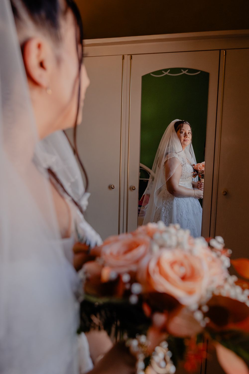 A wedding bouquet of peach roses and white flowers being held in a soft-focus shot.