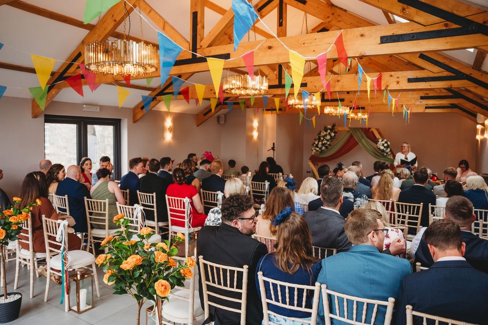 Wedding reception venue with chandelier lighting and white chairs set up for guests. Gellifawr Woodland Retreat