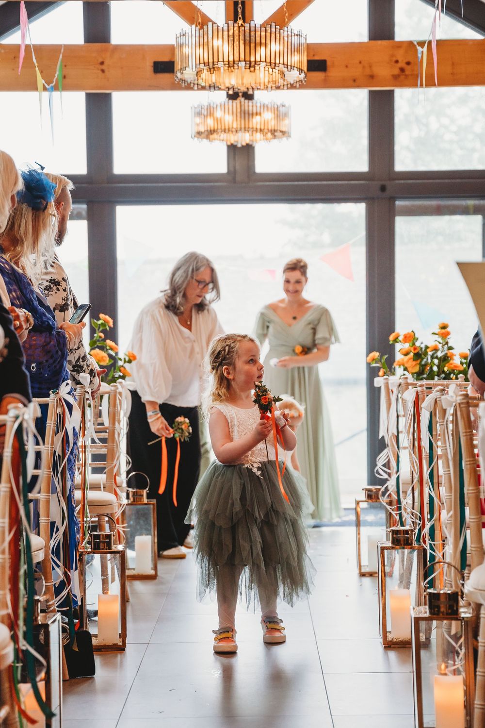 Wedding venue decorated with floral arrangements and ribbon-adorned chairs along the aisle.