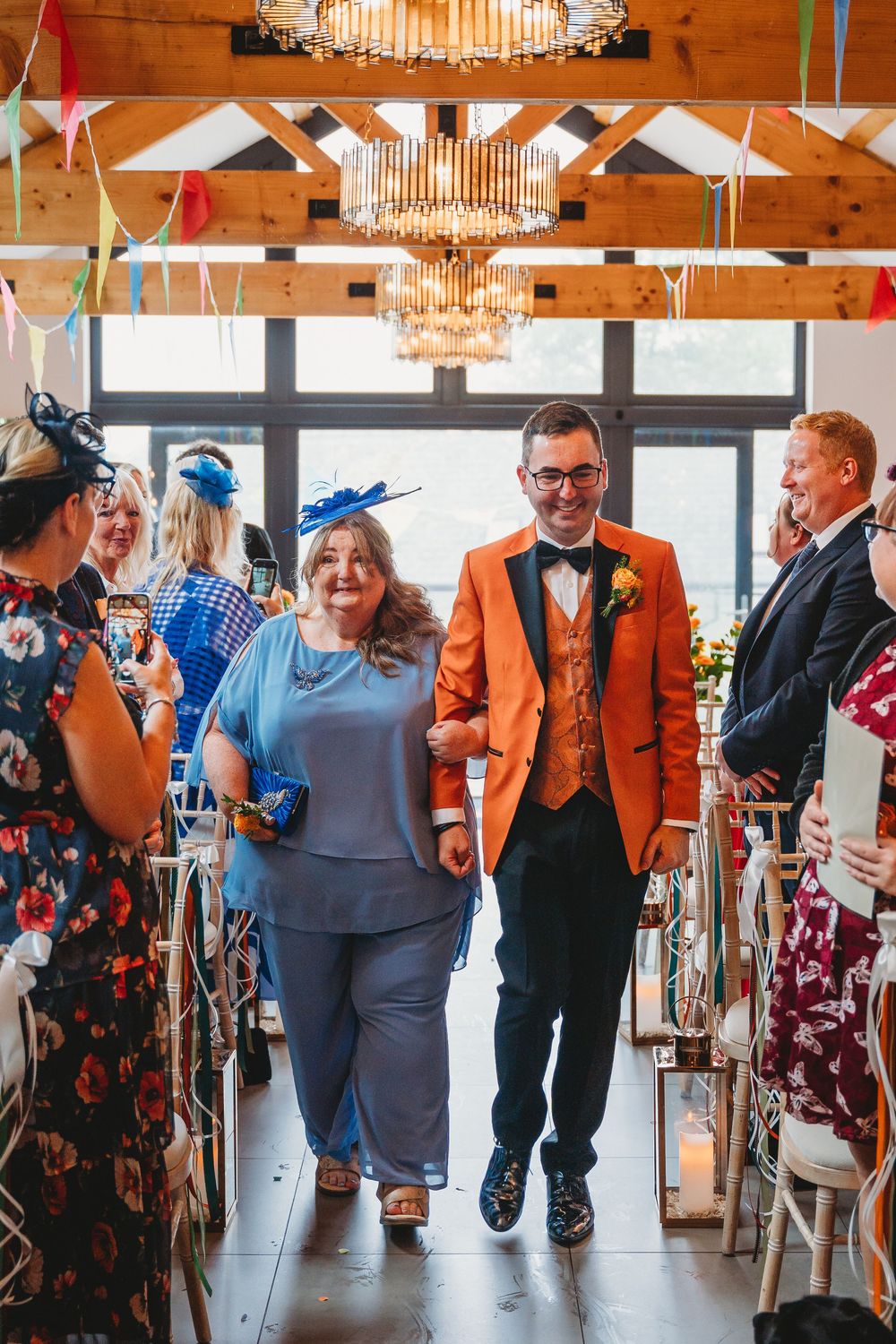 Groom entrance in his orange suit at his gay wedding Gellifawr Woodland Retreat