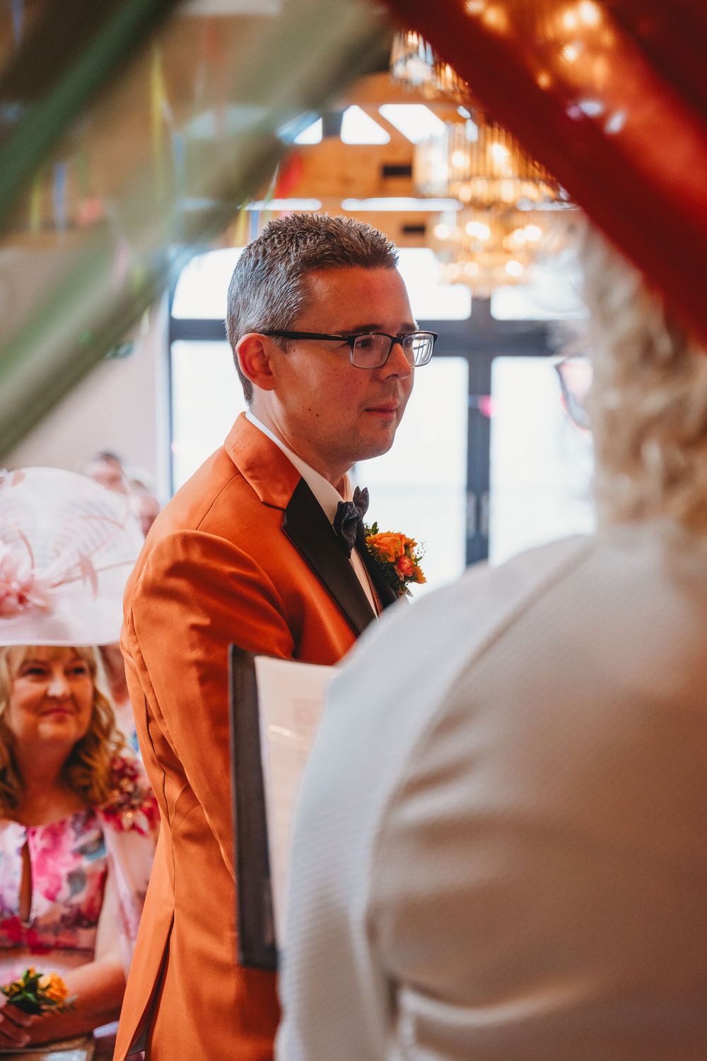 Groom wearing a bright orange jacket at gay wedding Gellifawr Woodland Retreat