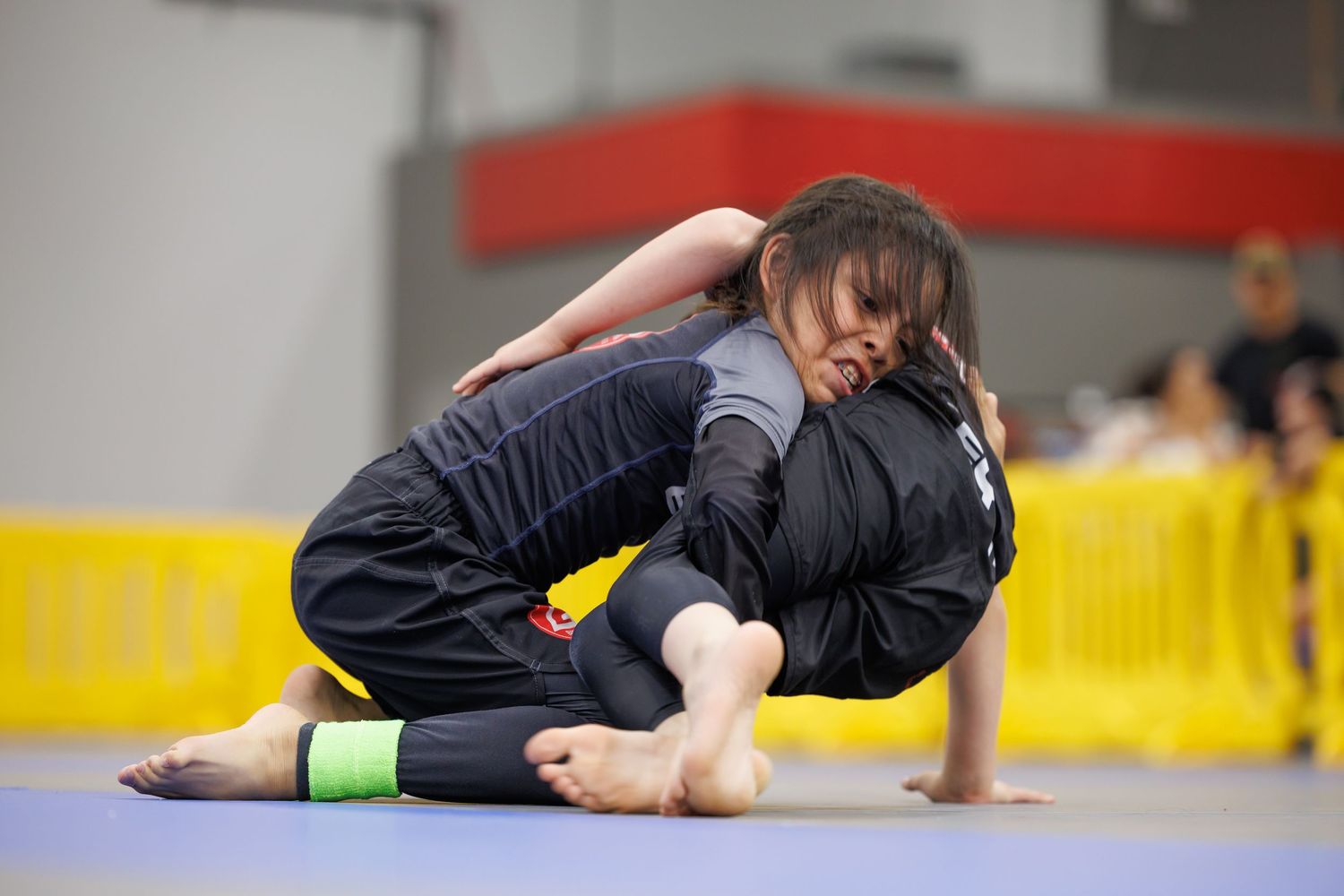 Martial artists demonstrating advanced grappling techniques on competition mats.