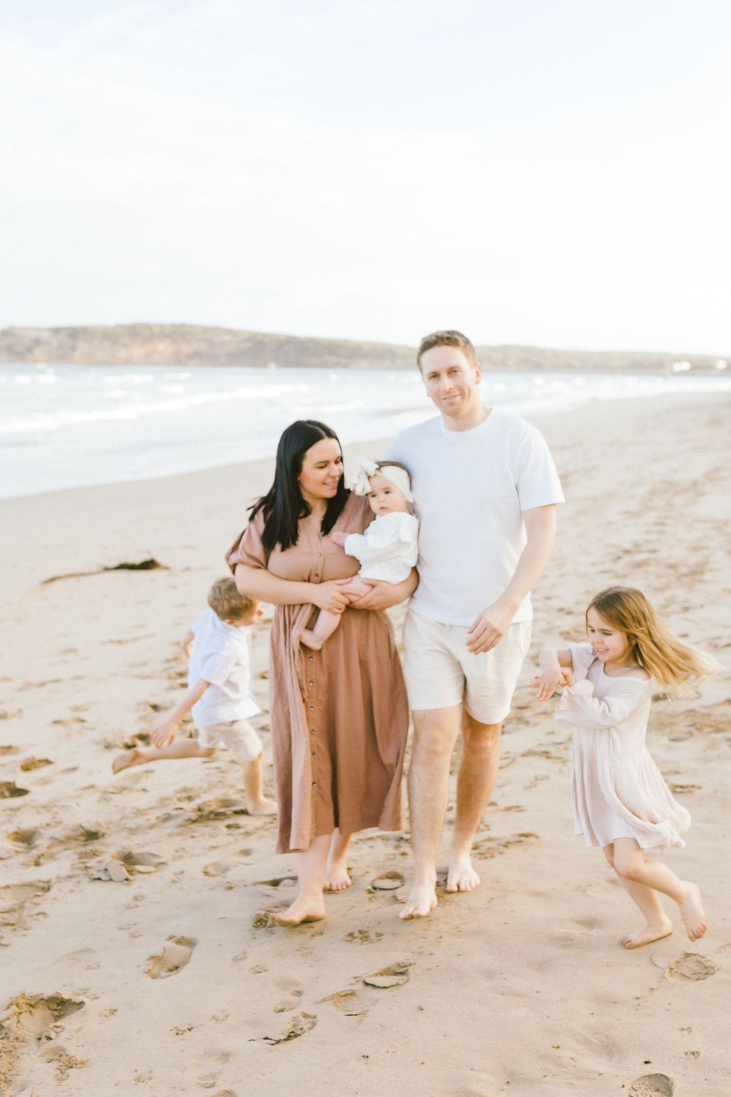 Family enjoying a tender moment together while walking along a sandy beach at sunset.