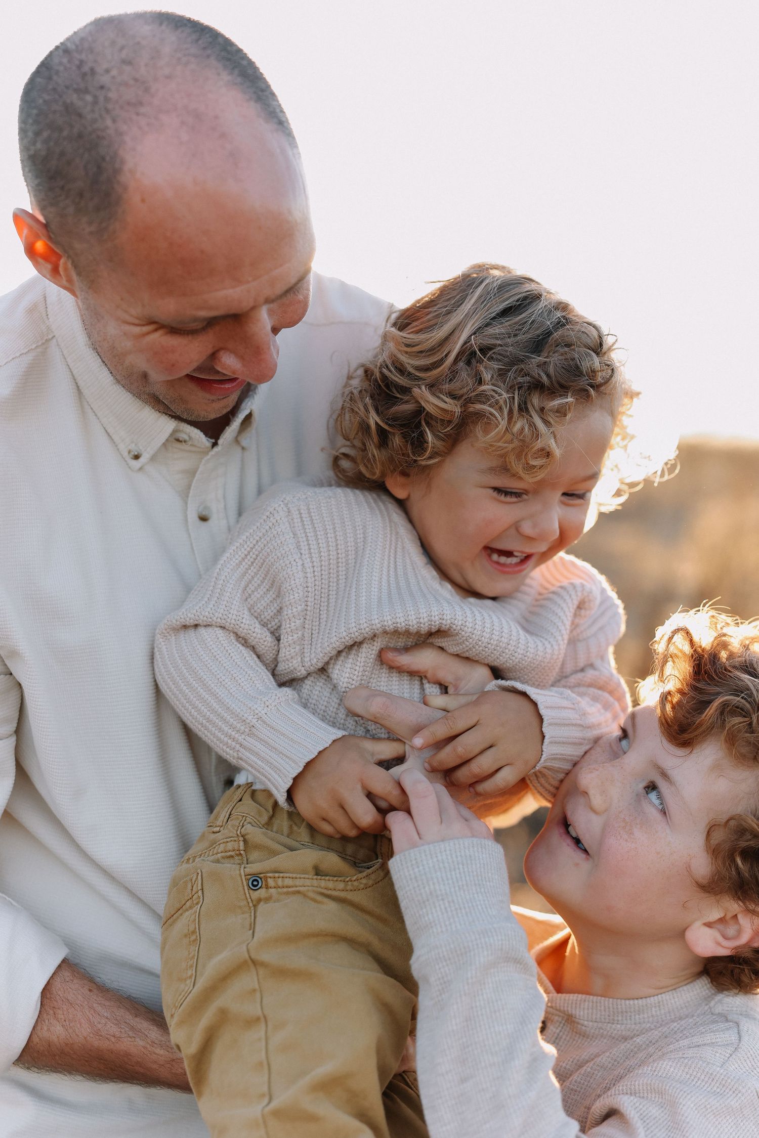 A loving family moment captured during golden hour as they embrace and share laughter together outdoors.