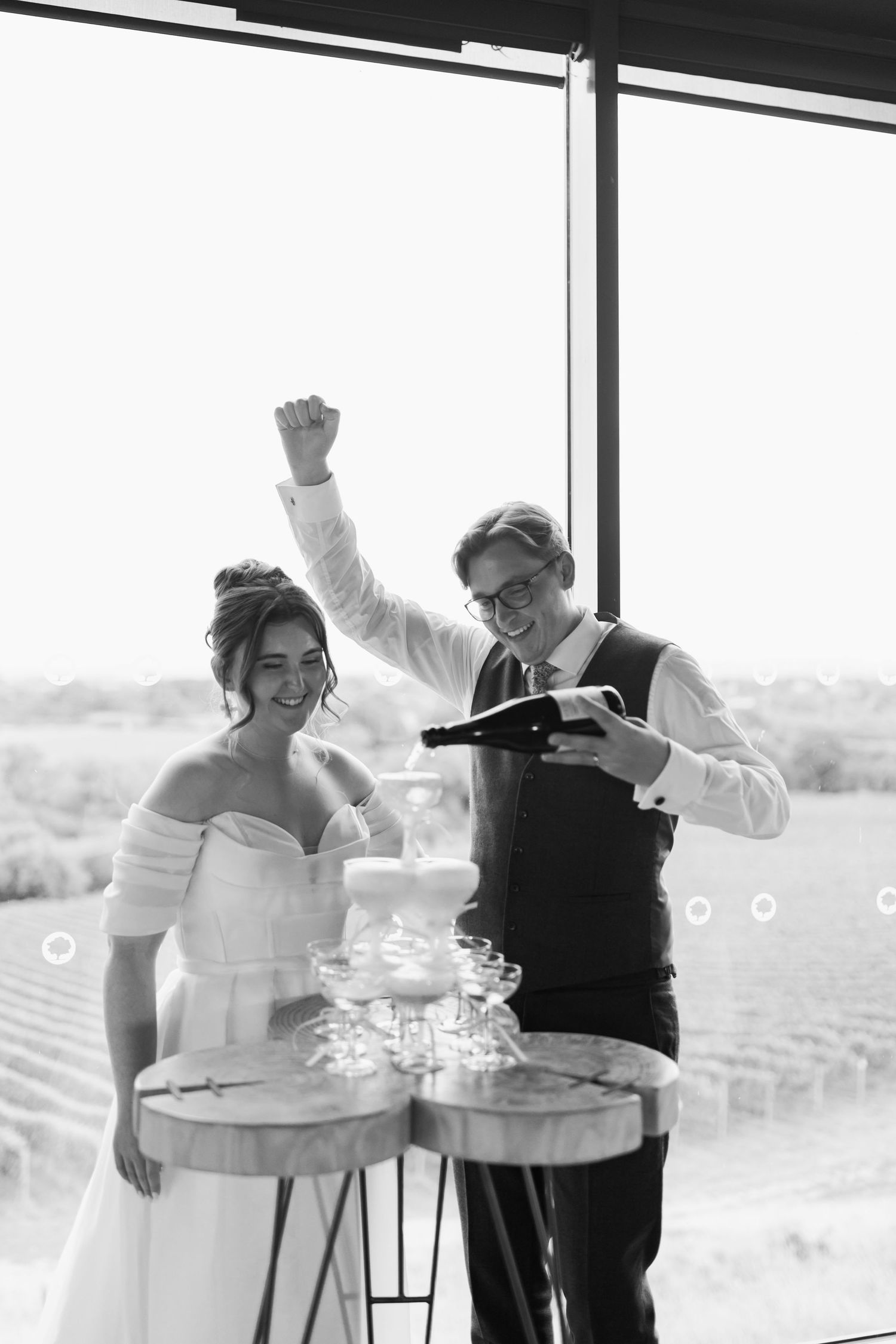 A couple in wedding attire shares a joyful dance moment during their celebration at a scenic outdoor venue.