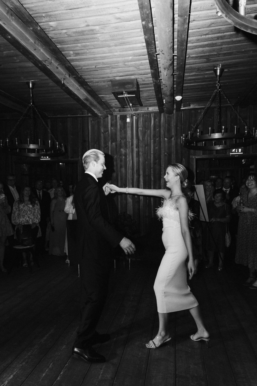 Wedding reception dance captured in black and white in rustic wooden venue.