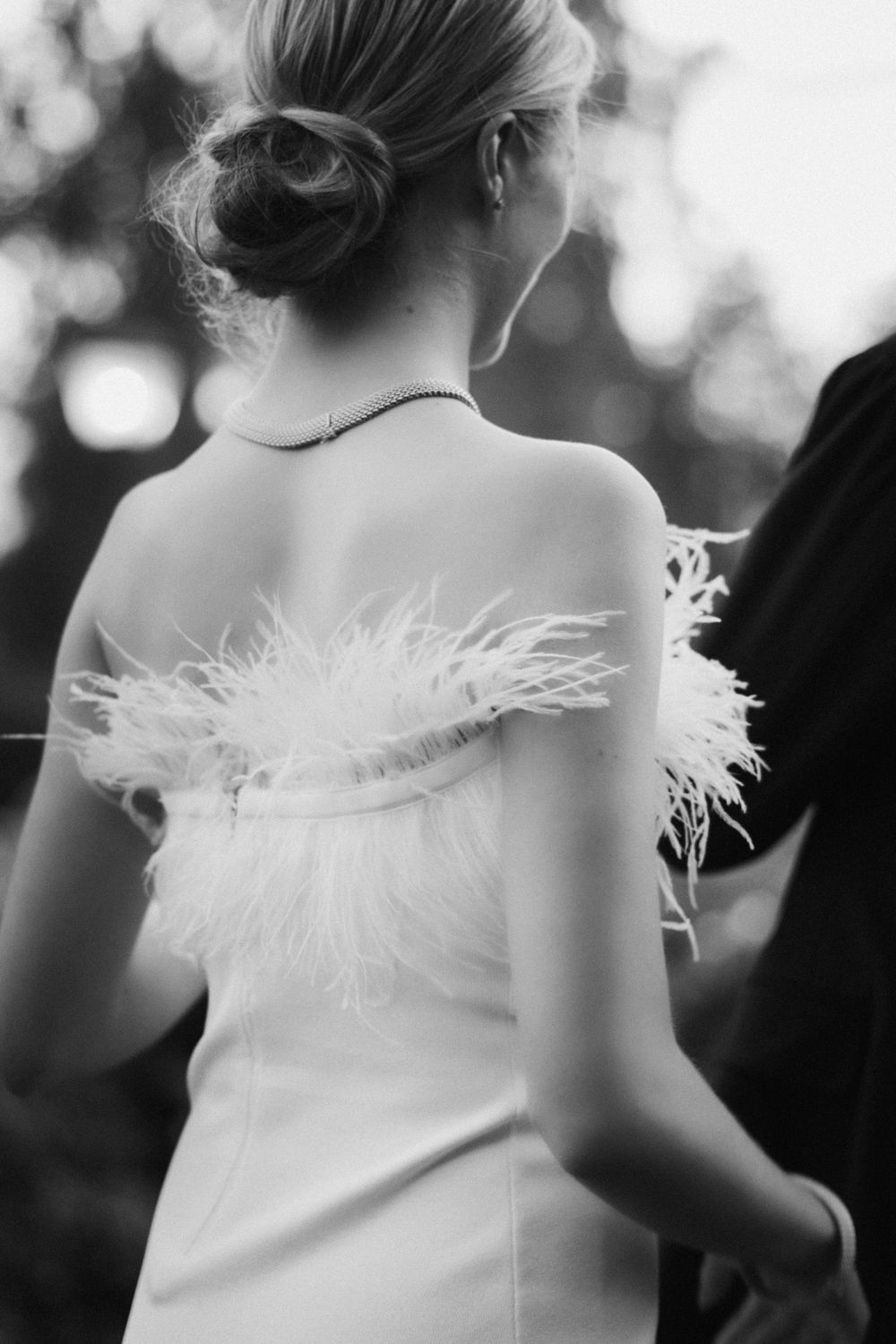Black and white photo of a wedding dress with feather trim details.