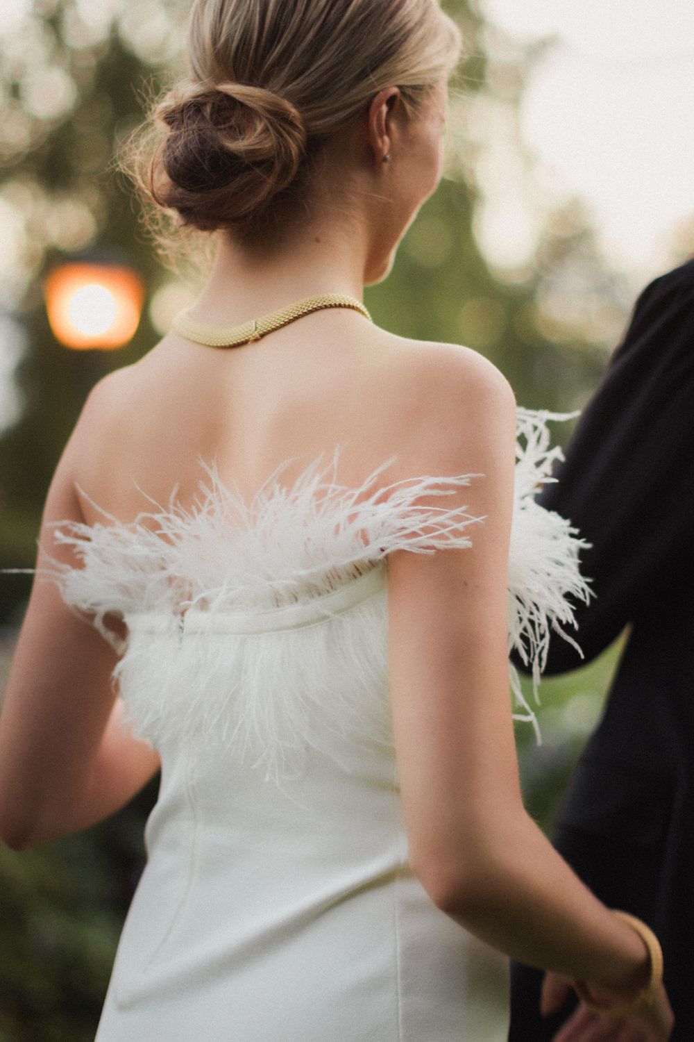White wedding dress with feathered trim detail captured in outdoor lighting.