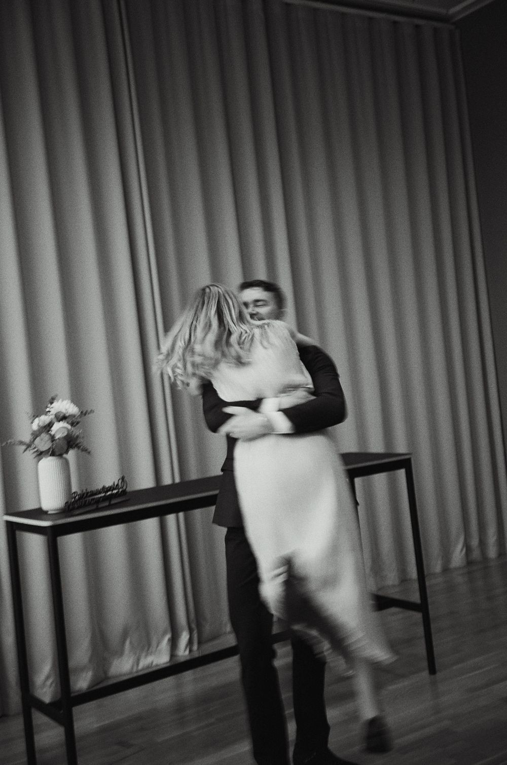 Artistic black and white performance sequence showing movement across tables on stage.