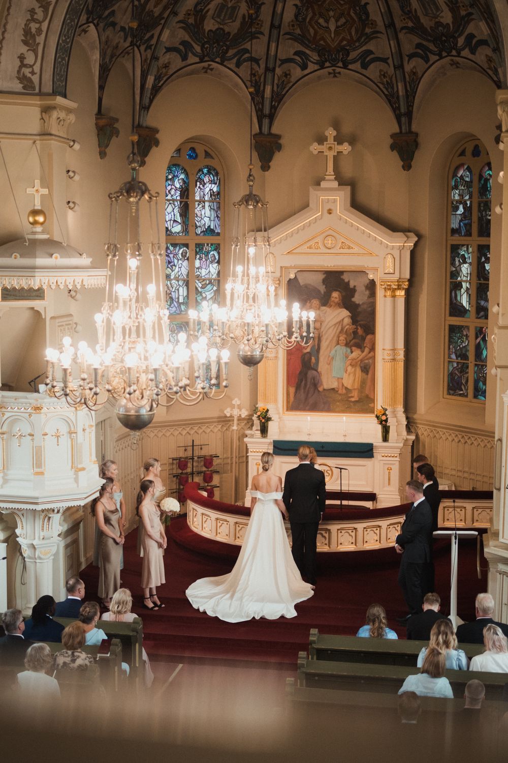 Wedding ceremony in a historic church with ornate architecture and crystal chandeliers.