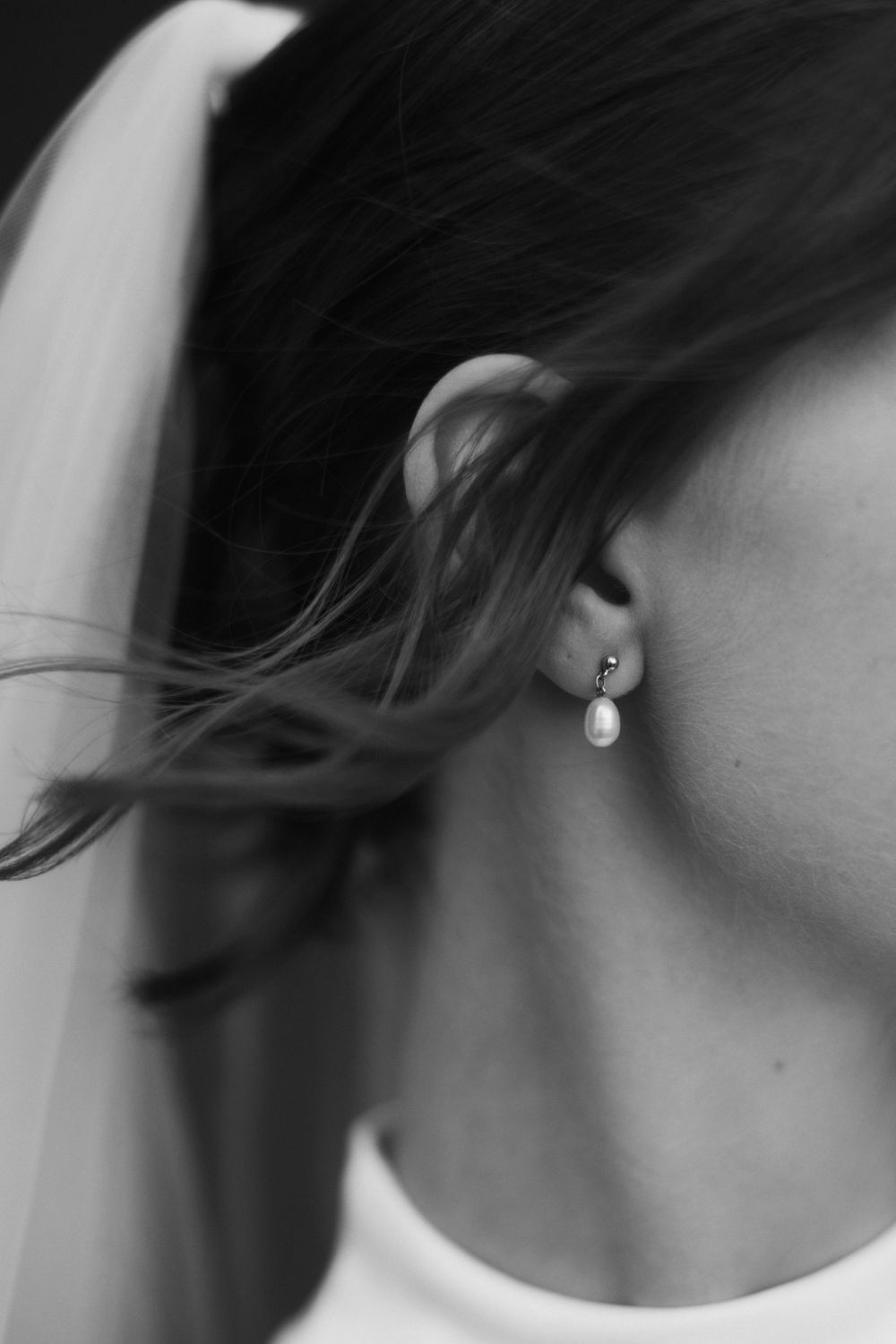 Close-up black and white profile shot showing an elegant pearl drop earring.
