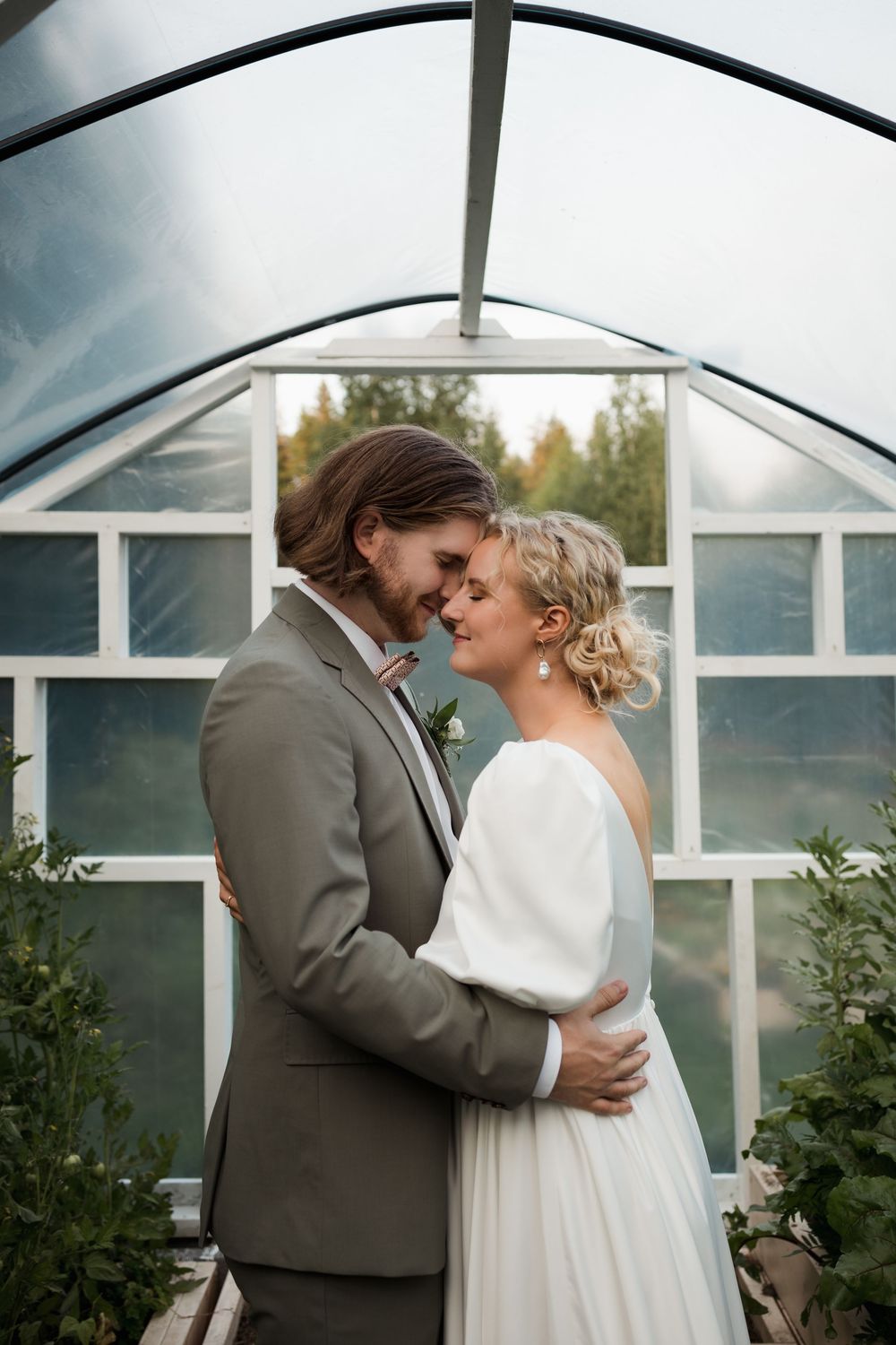 Romantic greenhouse wedding portrait showing intimate moment between couple.