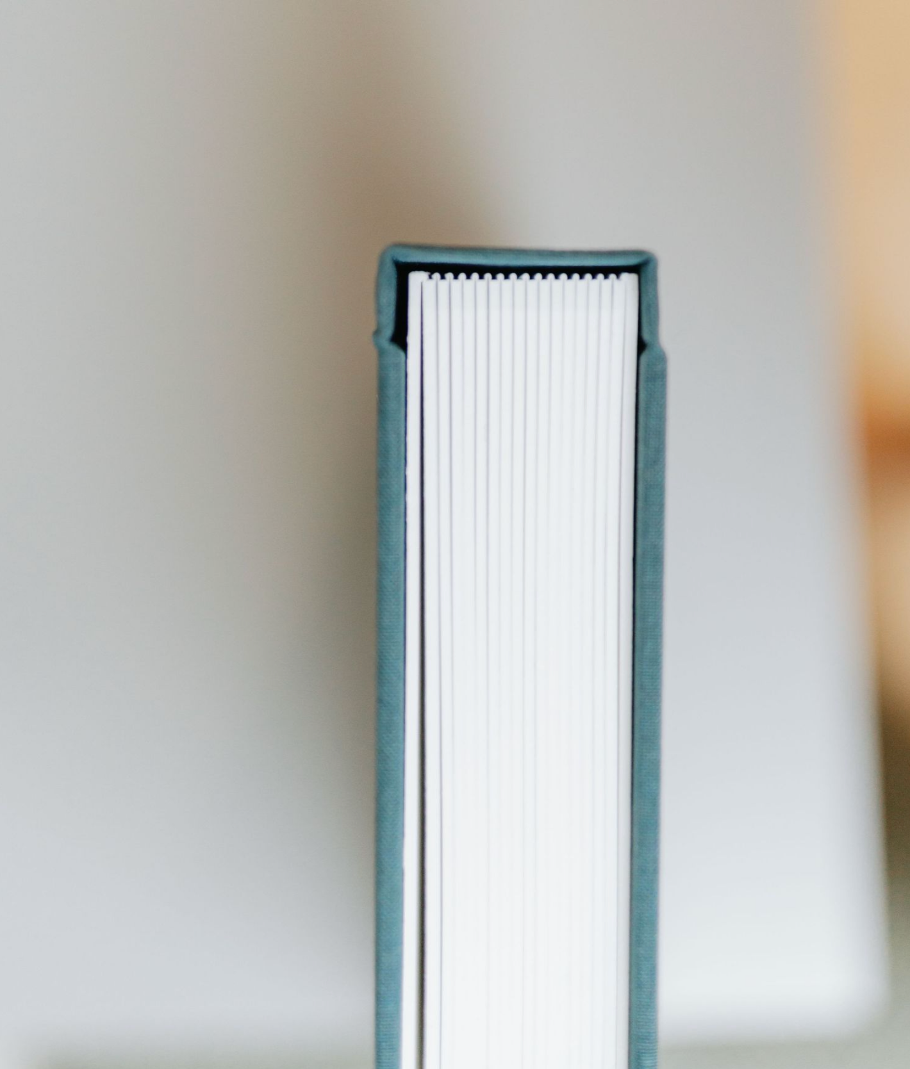 A series of four minimalist white book spines arranged horizontally against a blurred beige background.