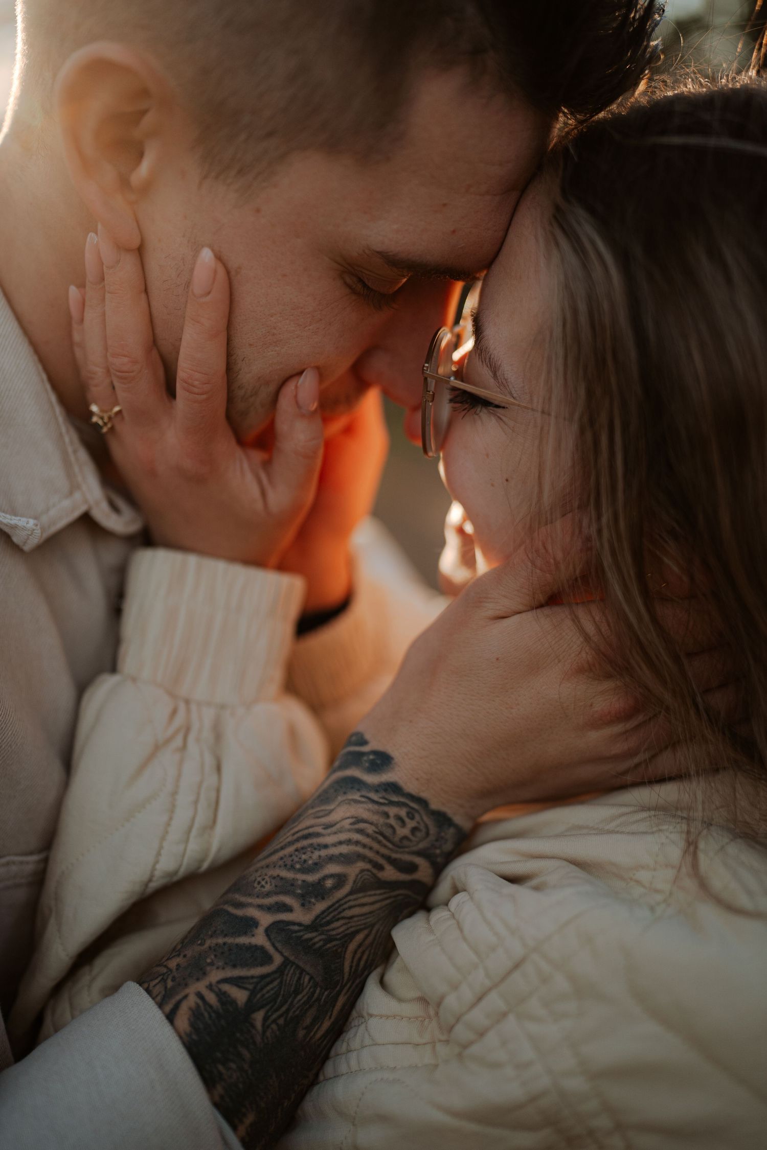 Intimate romantic couple sharing tender kisses in moody lighting with warm orange glow.