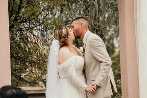 Romantic wedding couple shares intimate moments in a lush garden setting with palm trees and soft lighting.