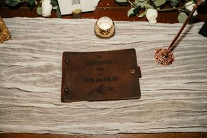Leather wedding details and accessories arranged on a rustic white wooden surface.