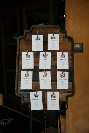 Wedding seating chart display with multiple paper cards arranged on a dark wooden board.