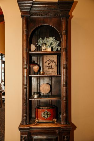 Vintage wooden display cabinet with ornate carvings and decorative items on shelves.