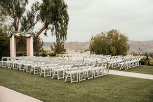 White chairs arranged in rows on a lawn for an outdoor wedding ceremony with mountain views.