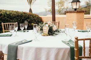 Elegant wedding reception tables set with white linens and place settings against a scenic backdrop.