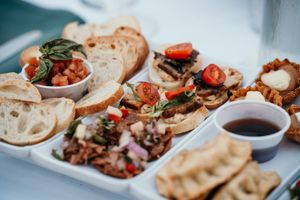 Close-up of appetizer plates featuring bruschetta and various toppings served at a wedding reception.