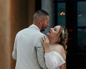 Romantic couple sharing an intimate dance moment at an outdoor evening wedding reception.