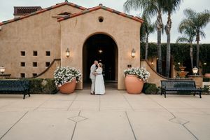 Spanish-style wedding venue exterior with terra cotta roof and palm trees at sunset creating a romantic ambiance.