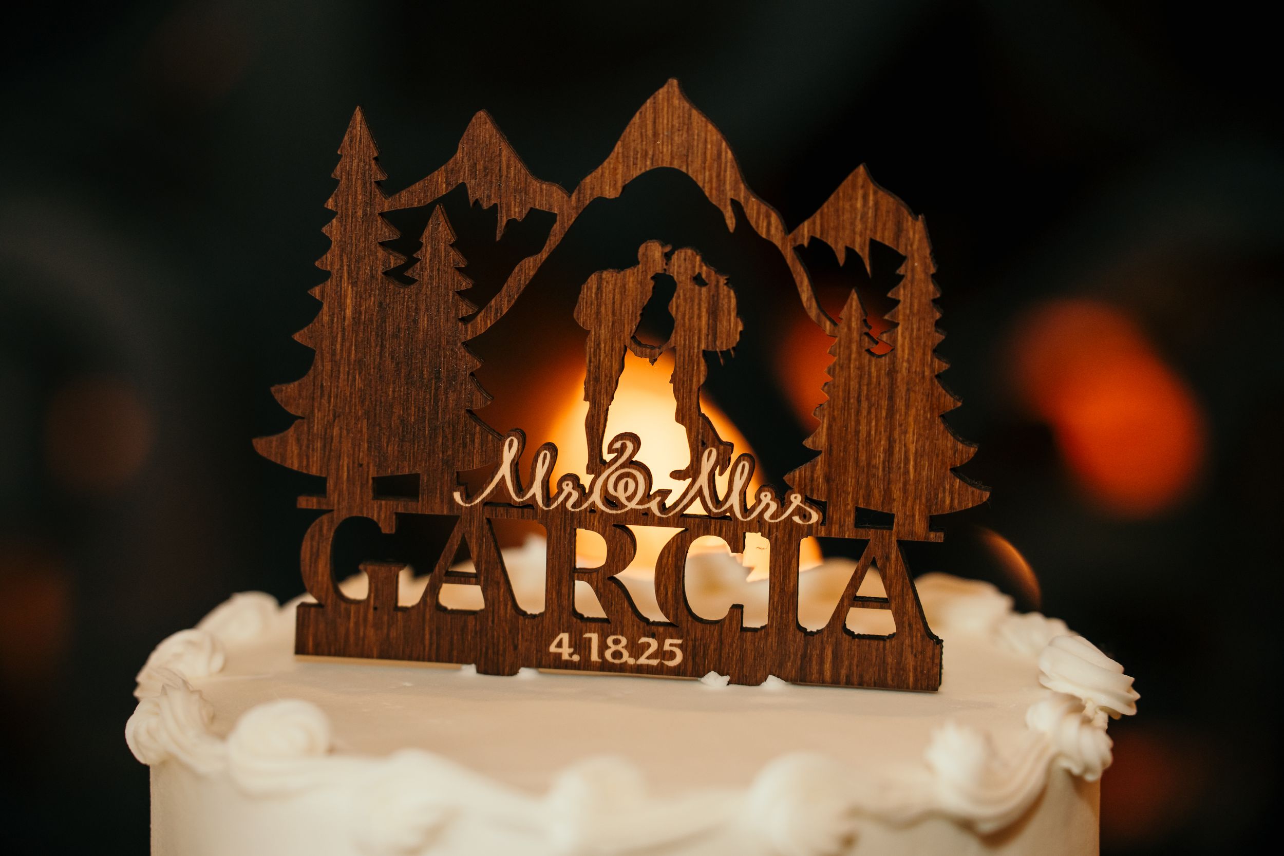 A silhouetted wooden Christmas decoration with a nativity scene glows warmly against a dark background.