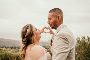 Newlyweds sharing intimate moments in an outdoor garden setting with mountain views.