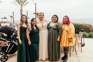 Wedding party members gathered outdoors wearing coordinated green and yellow dresses.