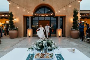 Outdoor wedding reception venue with string lights and Mediterranean-style architecture.