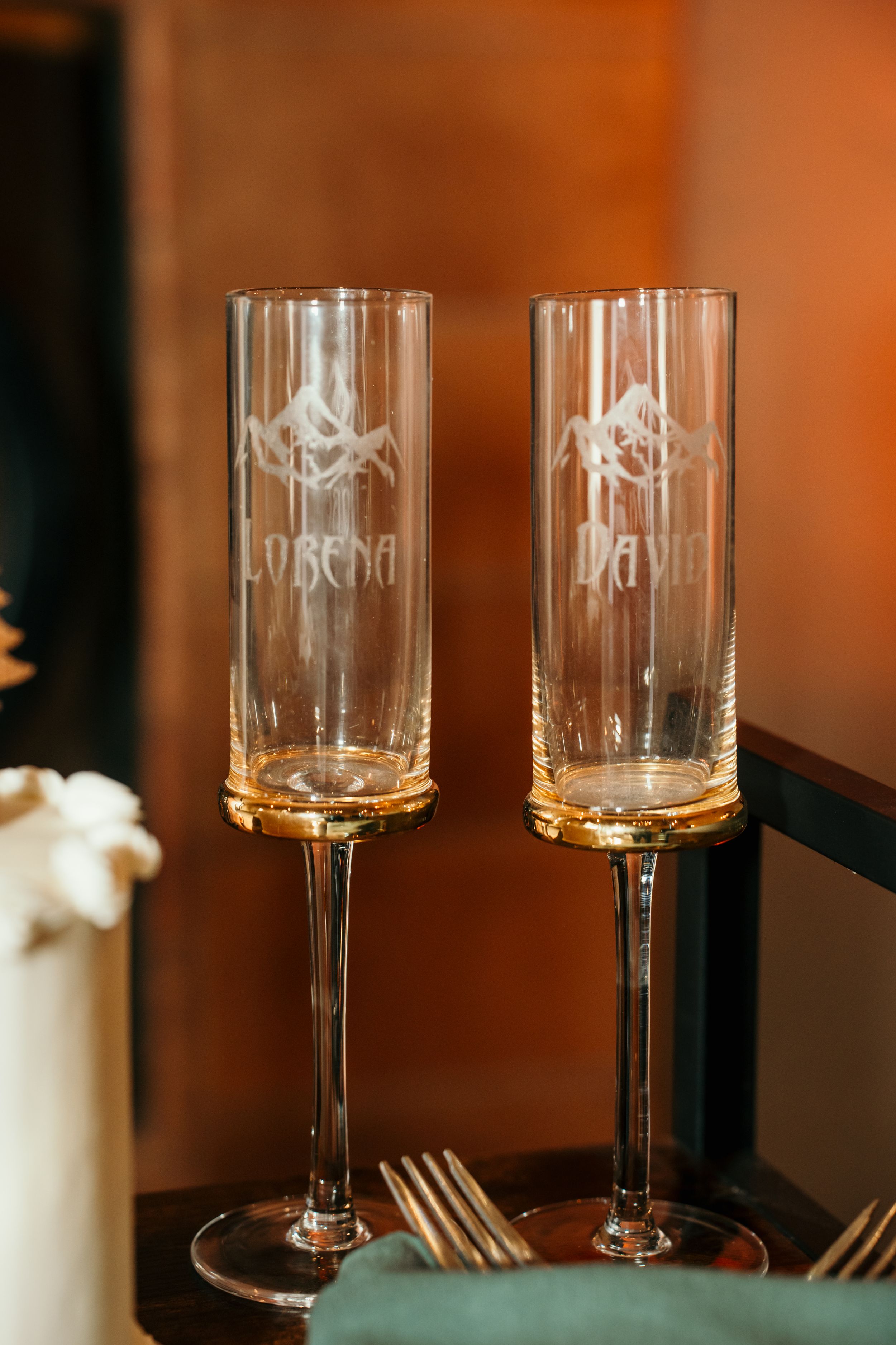 Elegant etched wine glasses displayed on a dark wooden surface with warm ambient lighting.