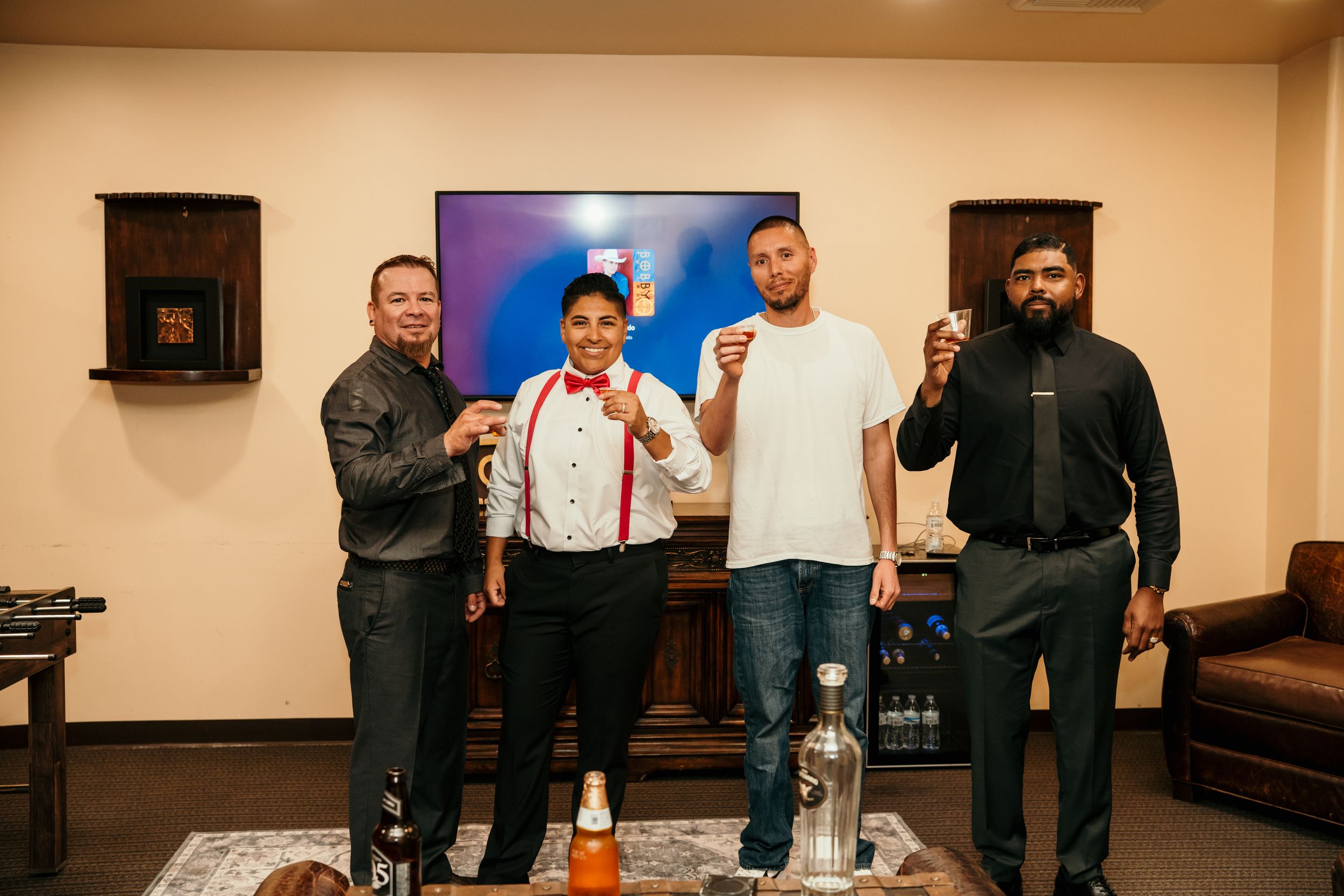 A group of four people posing together in a casual indoor setting with a leather couch and wall decor.