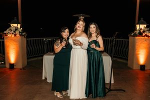 Wedding party in emerald green and white attire celebrating during evening reception.