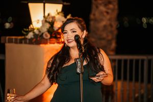 Wedding entertainment performer singing on stage with dramatic orange lighting.