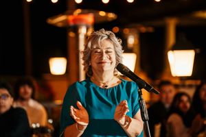 Evening wedding reception with warm lighting and guests enjoying speeches at tables.