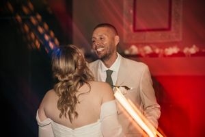 Wedding dance floor scene illuminated with red lighting creating a romantic atmosphere.