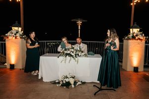 Outdoor wedding venue decorated with string lights and white linens for evening celebration.