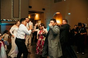 Couples dance together in a dimly lit ballroom during a formal evening event.