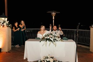 Evening wedding reception space with illuminated columns and decorated head table.