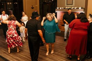 People dancing and celebrating on a wooden dance floor at a wedding reception.