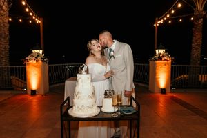 Romantic nighttime wedding scene with glowing orange lights and intimate cake cutting moment.