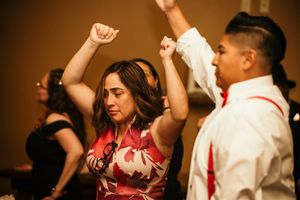 People dancing and celebrating at what appears to be a wedding reception or party with warm lighting.