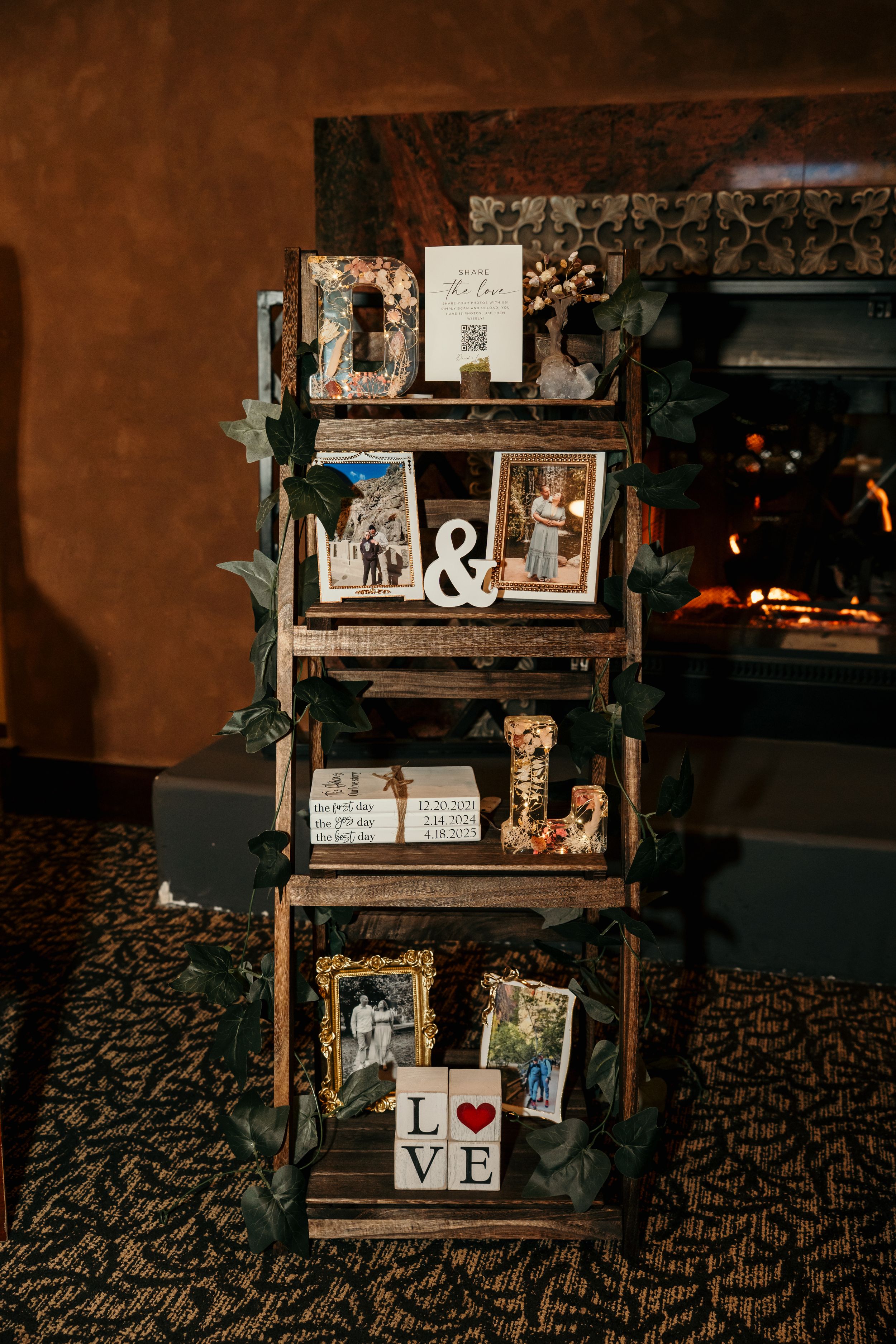 Wedding decor display featuring vintage frames, LOVE letters, and rustic elements on a dark patterned carpet.
